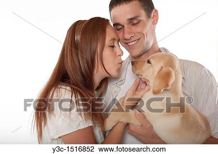 Stock Image - Young couple with labrador retriever puppy. Fotosearch