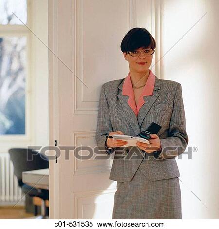 Young executive woman with grey dress in front of an office white door View Large Photo Image Stock Photography - Young executive woman with grey dress in front of an office white door. Fotosearch