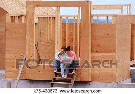 Stock Image - young family looking at blueprint of their new home. Fotosearch