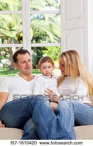 Young family sitting on their sofa at home View Large Photo Image Stock Image - Young family sitting on their sofa at home. Fotosearch