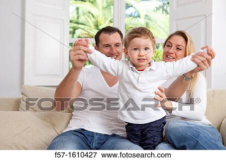 Stock Photo - Young family sitting on their sofa at home. Fotosearch