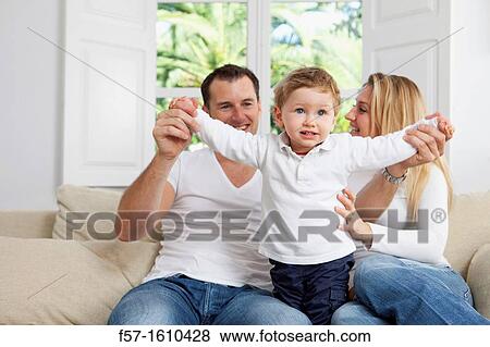 Stock Photo - Young family sitting on their sofa at home. Fotosearch