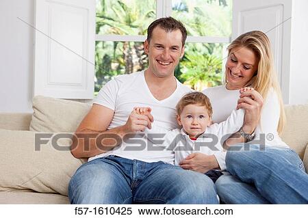 Stock Photography - Young family sitting on their sofa at home. Fotosearch