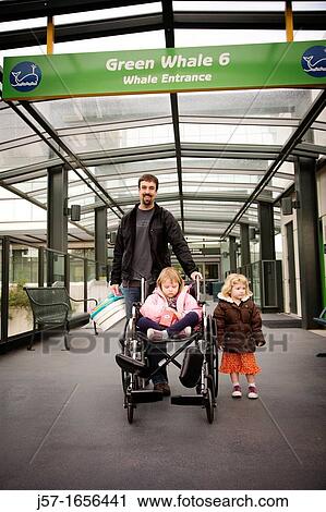 Young family waiting to be picked up outside Seattle Childrens Hospital after receiving chemo therapy treament. The little girl on the right is potty training so the father is holding a portable potty. View Large Photo Image Stock Image - Young family waiting to be picked up outside Seattle Childrens Hospital after receiving chemo therapy treament. The little girl on the right is potty training so the father is holding a portable potty.. Fotosearch