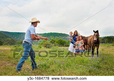 Young farmer family - dad is roping in his wife and children with horse in the background View Large Photo Image Stock Photo - Young farmer family - dad is roping in his wife and children with horse in the background. Fotosearch
