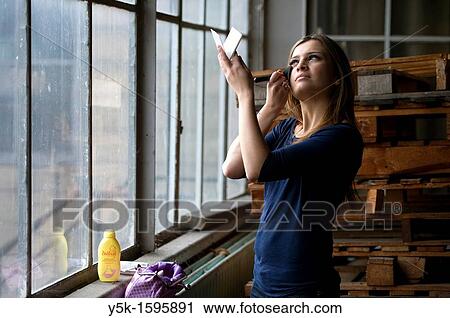 Young, fashionable, Afghan woman, living in asylum in the Netherlands, posing near the docks of Rotterdam harbor, doing her make-up near a window of an old, abandoned industrial building View Large Photo Image Stock Image - Young, fashionable, Afghan woman, living in asylum in the Netherlands, posing near the docks of Rotterdam harbor, doing her make-up near a window of an old, abandoned industrial building. Fotosearch