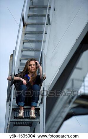 Young, fashionable woman from Afghanistan, living in asylum in the Netherlands, posing near the docks of Rotterdam harbor, sitting on the stairs of a harbor-crane. View Large Photo Image Picture - Young, fashionable woman from Afghanistan, living in asylum in the Netherlands, posing near the docks of Rotterdam harbor, sitting on the stairs of a harbor-crane.. Fotosearch