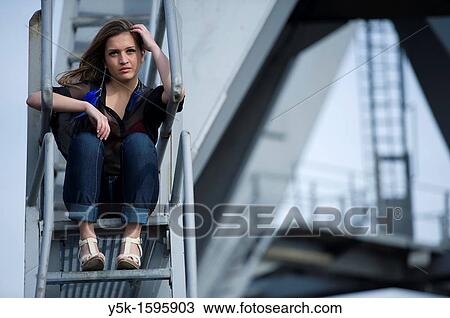 Young, fashionable woman from Afghanistan, living in asylum in the Netherlands, posing near the docks of Rotterdam harbor, sitting on the stairs of a harbor-crane. View Large Photo Image Stock Image - Young, fashionable woman from Afghanistan, living in asylum in the Netherlands, posing near the docks of Rotterdam harbor, sitting on the stairs of a harbor-crane.. Fotosearch