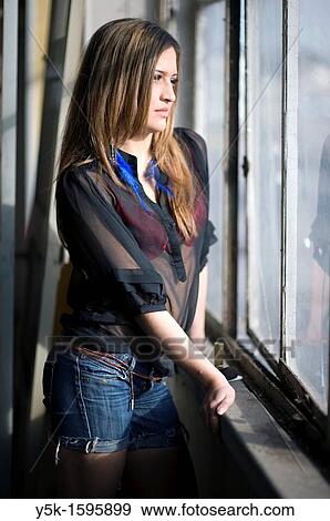 Young, fashionable woman from Afghanistan, living in asylum in the Netherlands, posing near the docks of Rotterdam harbor, leaning against the window of an old, abandoned industrial building. View Large Photo Image Stock Photo - Young, fashionable woman from Afghanistan, living in asylum in the Netherlands, posing near the docks of Rotterdam harbor, leaning against the window of an old, abandoned industrial building.. Fotosearch
