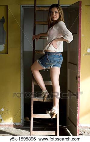 Young, fashionable woman from Afghanistan, living in asylum in the Netherlands, posing near the docks of Rotterdam harbor, climbing a a ladder to a storage-space in an old, abandoned industrial building. View Large Photo Image Stock Photograph - Young, fashionable woman from Afghanistan, living in asylum in the Netherlands, posing near the docks of Rotterdam harbor, climbing a a ladder to a storage-space in an old, abandoned industrial building.. Fotosearch