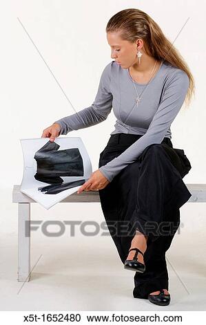 Stock Image - young Fashionable woman reads a fashion magazine. Fotosearch