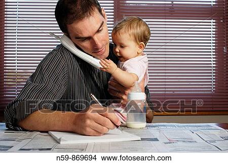 Young Father looking after baby while searching for work in the employment section of a newspaper View Large Photo Image Picture - Young Father looking after baby while searching for work in the employment section of a newspaper. Fotosearch