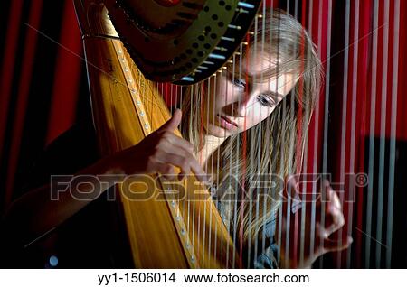 Picture - Young, female student at conservatoire playing harp at graduate level.. Fotosearch