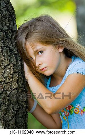 Stock Image - Young girl 6 years inclined to a tree. Fotosearch
