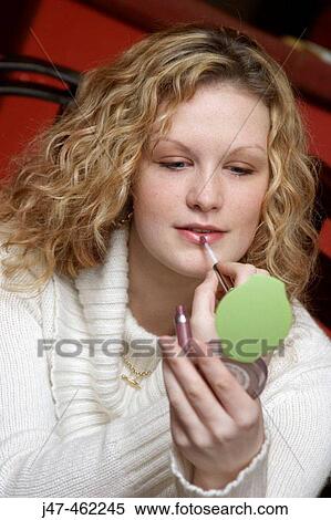 Young girl applying lipstick in a little mirror View Large Photo Image Stock Photography - Young girl applying lipstick in a little mirror. Fotosearch