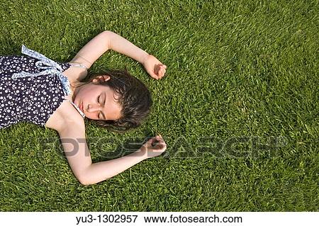 Young girl asleep on grass lawn on a hot summer day View Large Photo Image Stock Photo - Young girl asleep on grass lawn on a hot summer day. Fotosearch