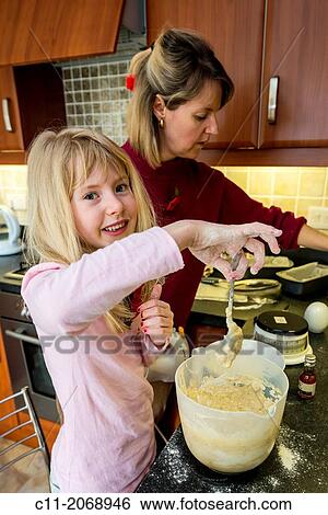 young girl baking in kitchen with mother, england, uk, europe. View Large Photo Image Stock Photograph - young girl baking in kitchen with mother, england, uk, europe.. Fotosearch