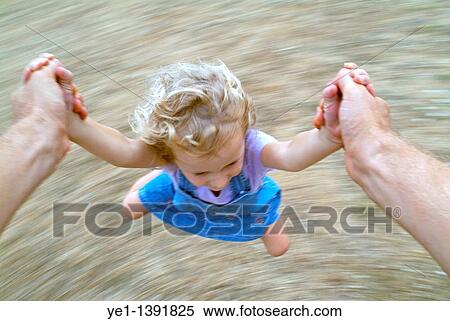 Stock Photography - Young girl being spun around by her father, France. Fotosearch