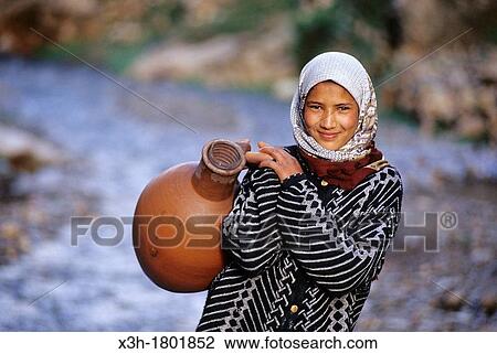 Stock Image - young girl carrying water in jar, Imi n Tala, High Atlas, Morocco, North Africa. Fotosearch