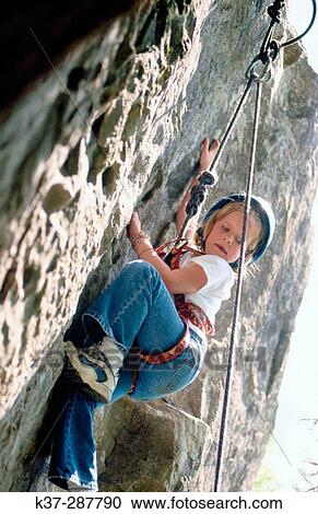 Young girl climbing rock face at rock climbing school View Large Photo Image Stock Image - Young girl climbing rock face at rock climbing school. Fotosearch