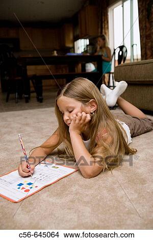 young girl does her homework on floor, older sister in background. View Large Photo Image Picture - young girl does her homework on floor, older sister in background.. Fotosearch
