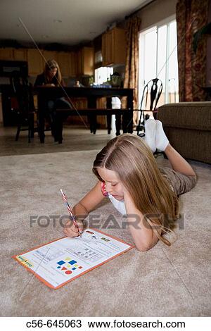 young girl does her homework on floor, mother in background. View Large Photo Image Stock Image - young girl does her homework on floor, mother in background.. Fotosearch