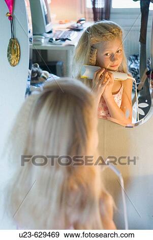 Young girl doing her hair. View Large Photo Image Stock Photo - Young girl doing her hair.. Fotosearch