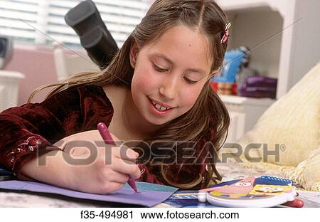 Stock Image - Young Girl Drawing in her Bedroom. Fotosearch