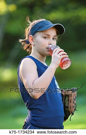 Picture - Young girl drinks sports drink to keep hydrated. Fotosearch
