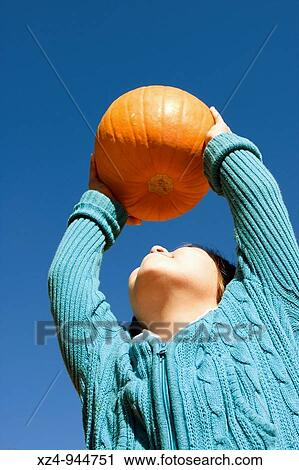 Stock Image - young girl finds the perfect pumpkin. Fotosearch
