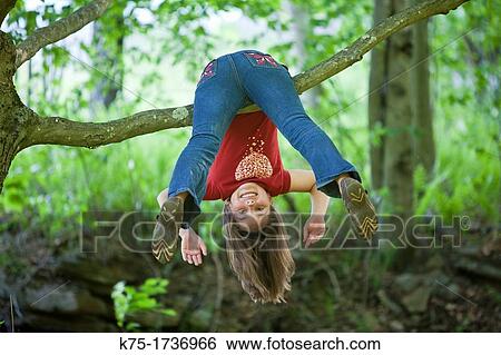 Young girl hanging upside down on branch of tree View Large Photo Image Stock Photograph - Young girl hanging upside down on branch of tree. Fotosearch