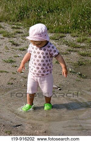 Young girl having fun in a puddle on a warm summer morning MR View Large Photo Image Stock Image - Young girl having fun in a puddle on a warm summer morning MR. Fotosearch