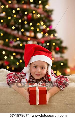 Young girl holding a gift at Christmas time View Large Photo Image Picture - Young girl holding a gift at Christmas time. Fotosearch