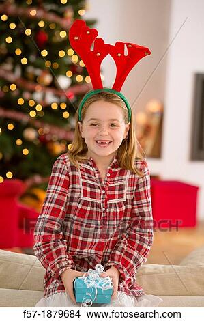 Young girl holding a gift at Christmas time View Large Photo Image Picture - Young girl holding a gift at Christmas time. Fotosearch