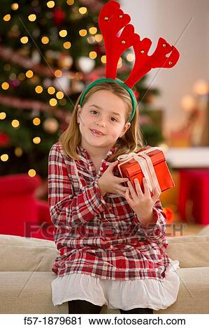 Stock Image - Young girl holding a gift at Christmas time. Fotosearch