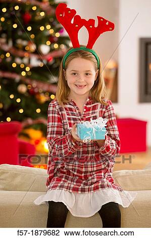 Stock Image - Young girl holding a gift at Christmas time. Fotosearch