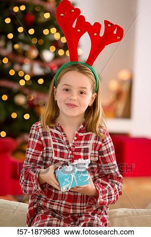 Young girl holding a gift at Christmas time View Large Photo Image Stock Image - Young girl holding a gift at Christmas time. Fotosearch