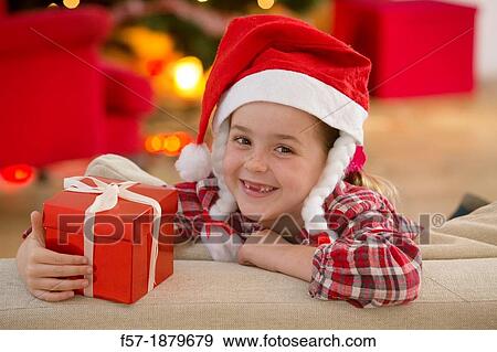 Stock Photo - Young girl holding a gift at Christmas time. Fotosearch