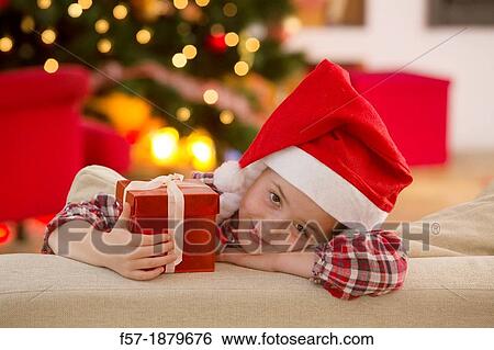 Stock Photograph - Young girl holding a gift at Christmas time. Fotosearch