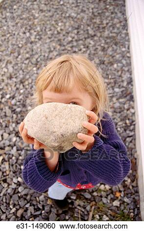 Young girl holding a rock View Large Photo Image Stock Image - Young girl holding a rock. Fotosearch
