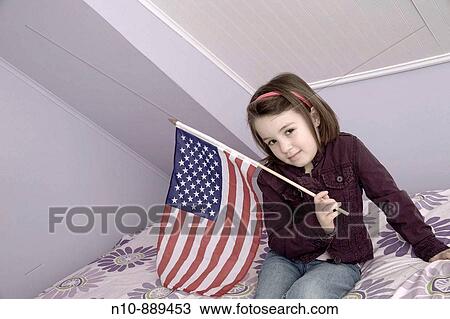 Stock Image - Young girl holding an American flag. Model and Property Released.. Fotosearch