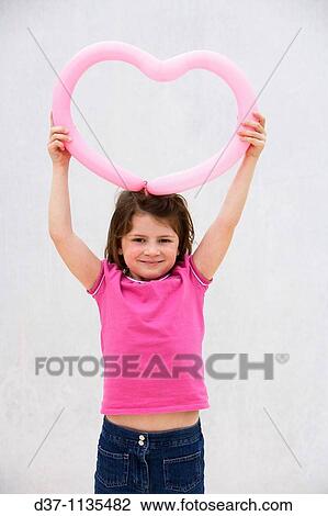 Stock Image - Young girl holding heart over her head. Fotosearch