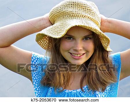 Stock Image - Young girl holding her straw hat. Fotosearch