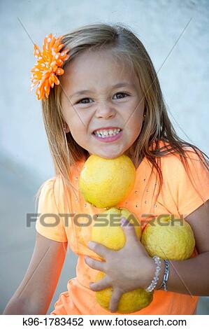 Stock Image - young girl holding lemmons. Fotosearch