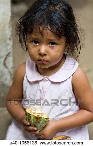 Stock Photograph - Young girl holding raw cacao pod. Fotosearch