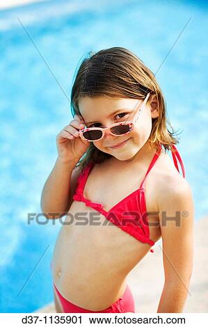 Stock Image - Young girl in bikini, looking over sunglasses. Fotosearch
