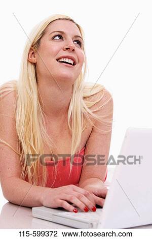 Young girl in her 20's on laptop day dreaming, typing and smiling View Large Photo Image Stock Image - Young girl in her 20's on laptop day dreaming, typing and smiling. Fotosearch