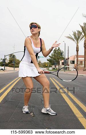 Young girl in her 20's playing tennis on the street blindfolded View Large Photo Image Stock Image - Young girl in her 20's playing tennis on the street blindfolded. Fotosearch