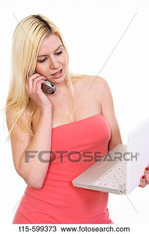Young girl in her 20's talking on phone and looking at her laptop at the same time View Large Photo Image Stock Image - Young girl in her 20's talking on phone and looking at her laptop at the same time. Fotosearch