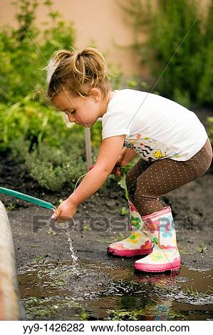 Stock Image - Young girl in the garden with hose - Cabanas Del Lago - Lake San Pablo, near Otavalo, Ecuador. Fotosearch